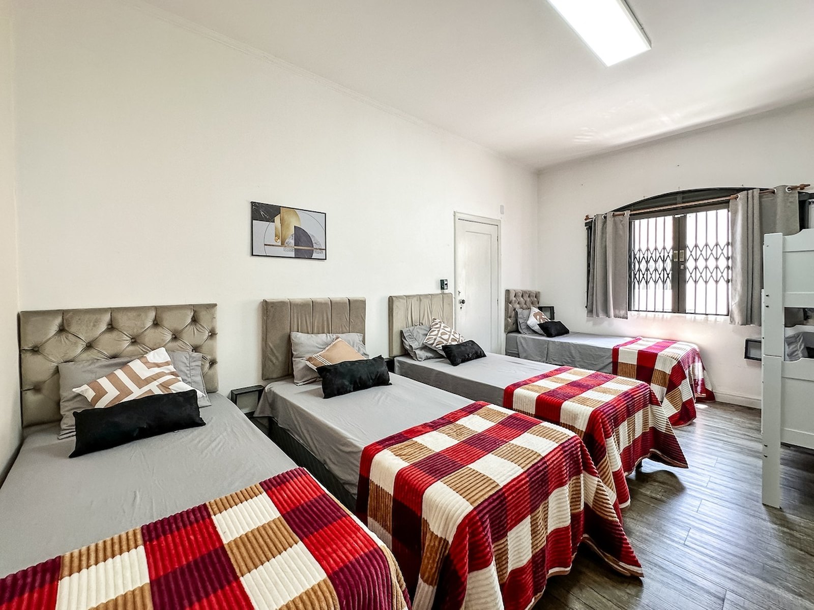 Quarto com quatro camas de solteiro e cabeceiras estofadas