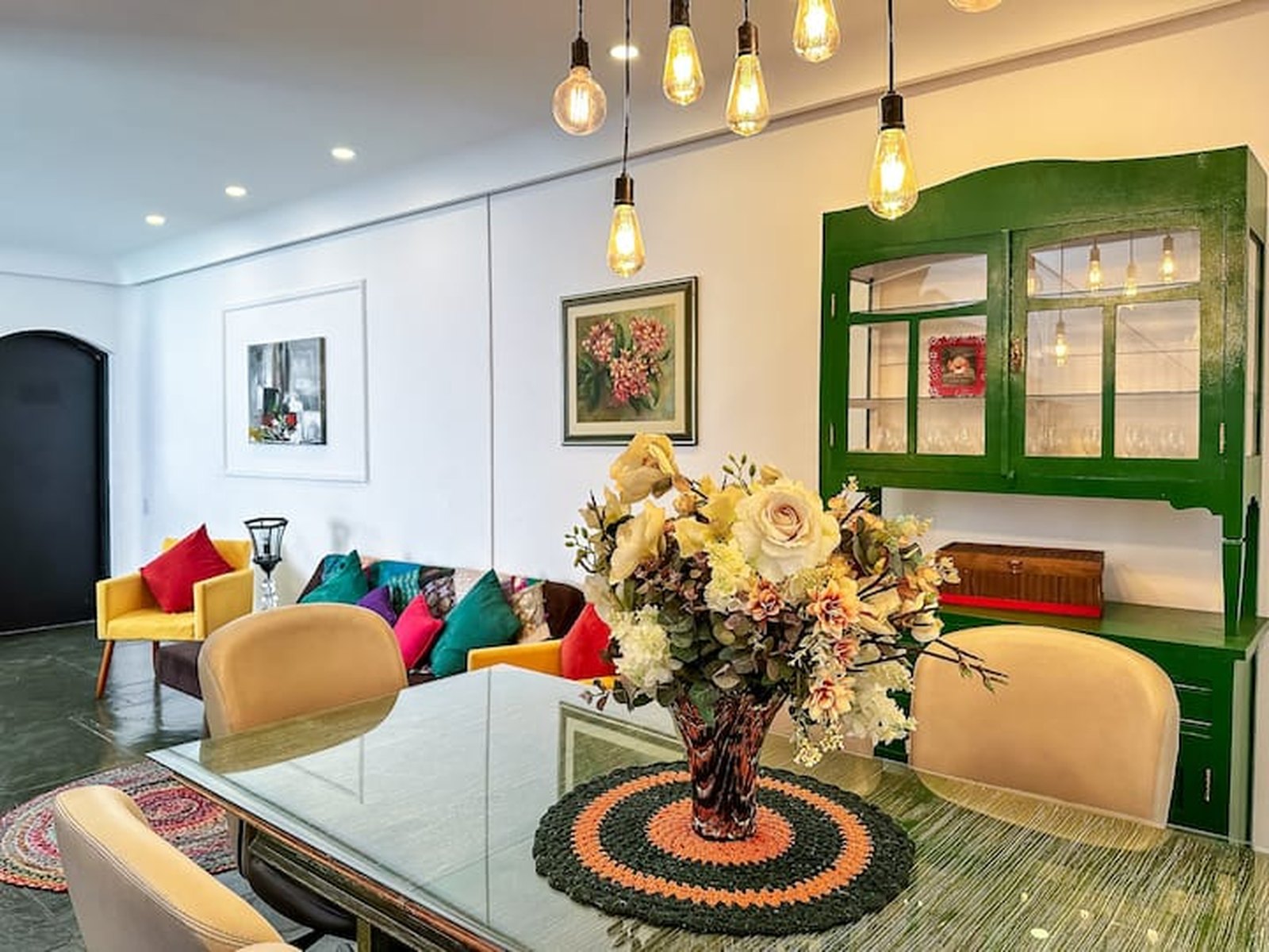 Sala de jantar com mesa de vidro e buffet verde